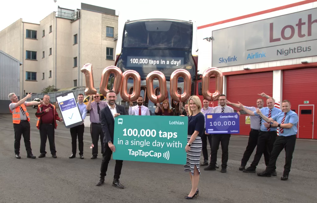 Balloons spell out 100,000 as Lothian staff stand in front of a bus to celebrate 100,000 contactless taps in a single day on its bus network